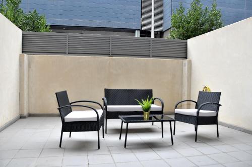 マドリードにあるOshun Sanchinarro Seasonal Living Loftsの椅子4脚と植物が置かれたテーブルのあるパティオ