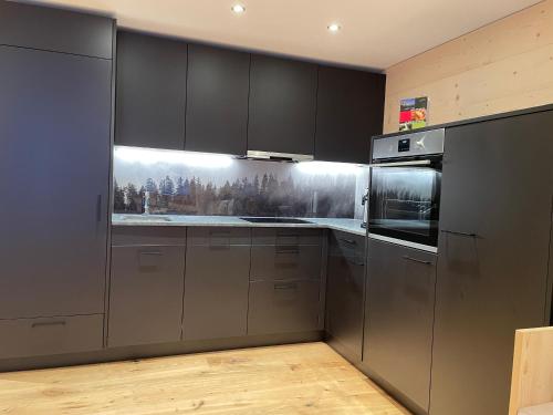 a kitchen with stainless steel appliances and black cabinets at Chalet La Montanara in Bettmeralp