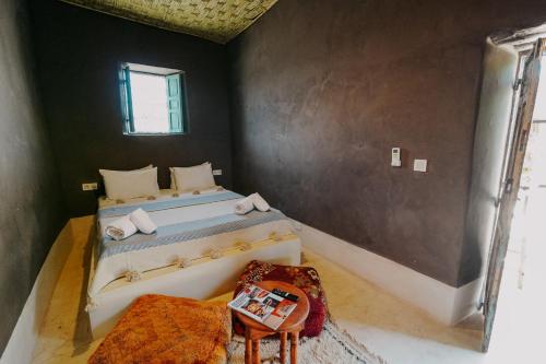 a bedroom with a bed and a table in it at Hotel & Spa La Ferme El Dar in Marrakech