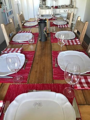 a long table with red and white plates and wine glasses at La Maison Bleue, luxury self-catering villa. in Langebaan