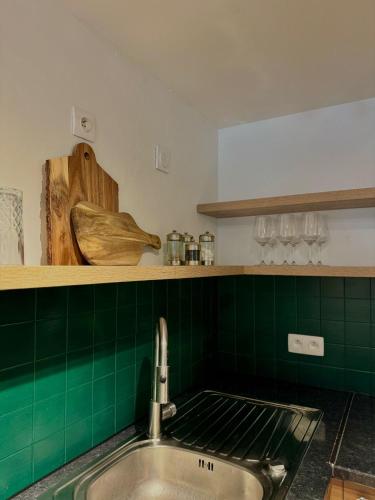 Il comprend une cuisine avec un évier et un mur carrelé vert. dans l'établissement Le Petit Social Home, à Chamonix-Mont-Blanc