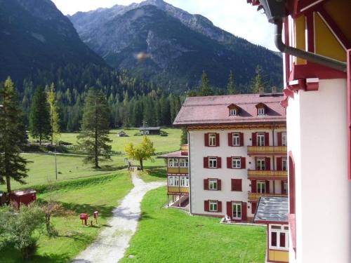 a building in a field with mountains in the background at Appartamento Dolomiti F5 complesso turistico in Carbonin