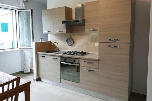 una cucina con mobili in legno e un forno a piano cottura di Alloggio turistico centro storico di Manziana a Manziana