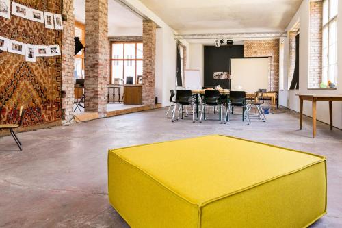 a yellow ottoman in a room with a table and chairs at Hotel Stadthaus Arnstadt in Arnstadt