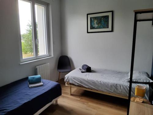 une chambre avec un lit, une chaise et une fenêtre dans l'établissement La blanche école, à Rochefort-sur-Loire