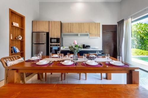 a dining room with a table and a kitchen at 宽敞舒适 邦涛海滩Laguna附近 四卧室私人泳池别墅 V07 in Phuket Town