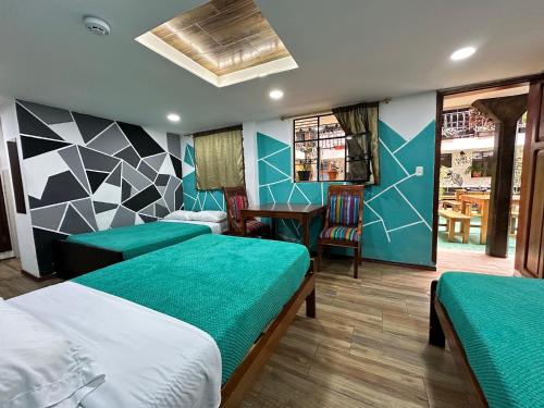 a room with two beds and a table and a desk at El Jardín Escondido by Soma in Baños