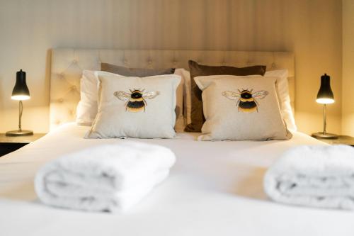 a bed with white pillows with two bees on them at Eden View Estate - Clubhouse Cottage in St. Andrews