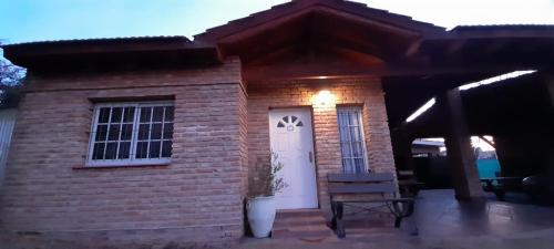 een stenen huis met een witte deur en een bank bij Cabaña La Cumbre Palermo in La Cumbre