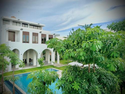 an exterior view of a house with a swimming pool and trees at STONE AGE Boutique in Kampot