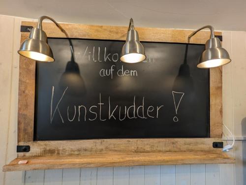 a chalkboard with a sign in a kitchen with three lights at Schute "Kunstkudder" im Hansehafen in Stade