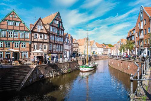 a canal in a city with buildings and a boat at Schute "Kunstkudder" im Hansehafen in Stade