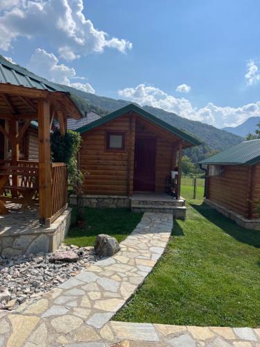 a log cabin with a stone walkway next to a house at Ethno House Bektesevic in Gusinje
