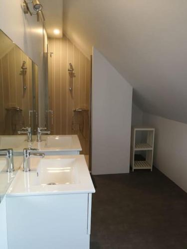 une salle de bain avec deux lavabos et un grand miroir dans l'établissement Gîte de la châtaigneraie, à Saint-Yrieix-la-Perche