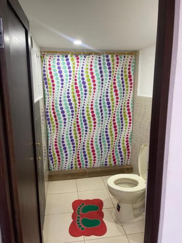 a bathroom with a colorful shower curtain with a toilet at El Jardín Escondido by Soma in Baños