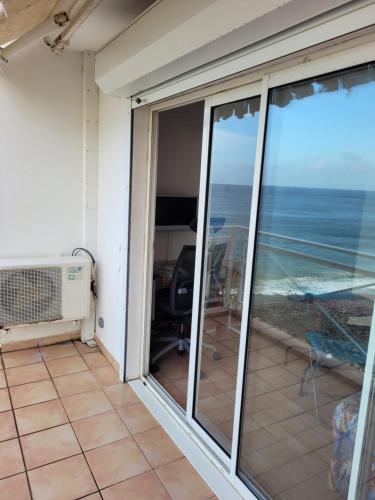 a balcony with sliding glass doors with a view of the ocean at Location studio vue exceptionnelle proximité mer in Gourbeyre