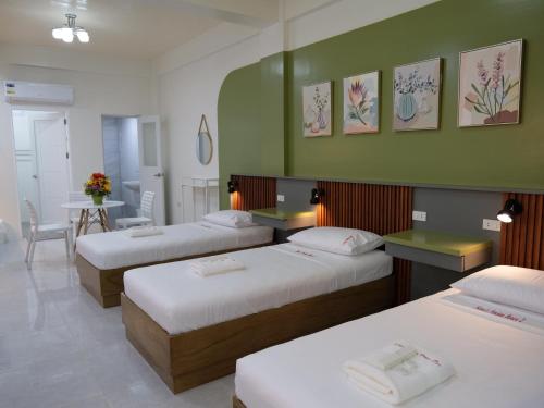 a hotel room with three beds and a table with a table at Karas Pension House East in Tuguegarao City