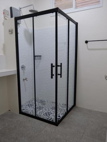 a shower with a glass door in a room at Karas Pension House East in Tuguegarao City