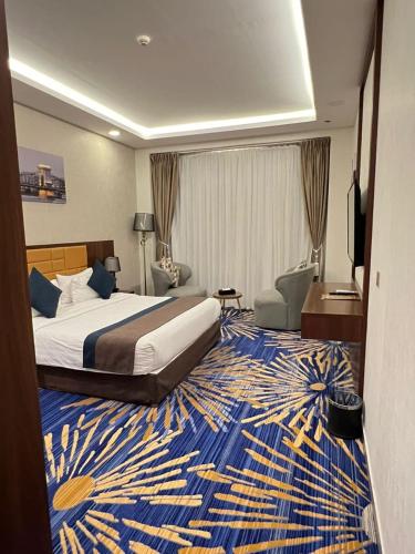 a hotel room with a bed and a blue and yellow rug at Holiday Al Khaleej Hotel in Al Khobar