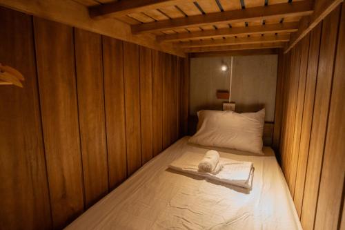 a small bed in a room with wooden walls at The Circle Hostel, La Union in San Fernando