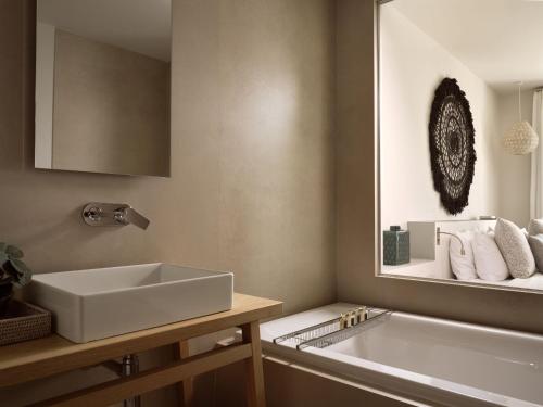 a bathroom with a sink and a tub and a mirror at Eagles Villas - Small Luxury Hotels of The World in Ouranoupoli