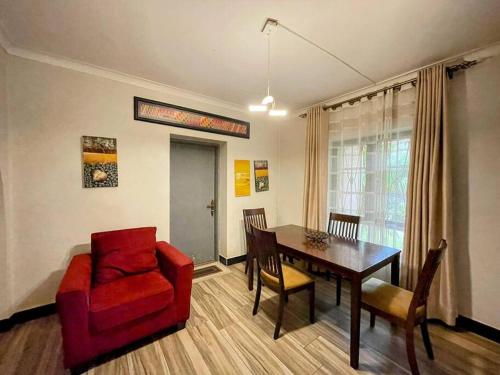 a living room with a dining room table and a red chair at The Uptown Villa in Kampala
