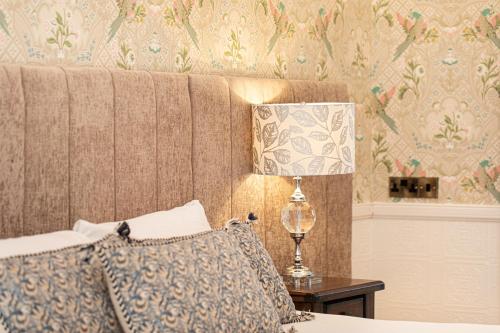 a bedroom with a bed and a lamp on a table at The Atholl Palace in Pitlochry