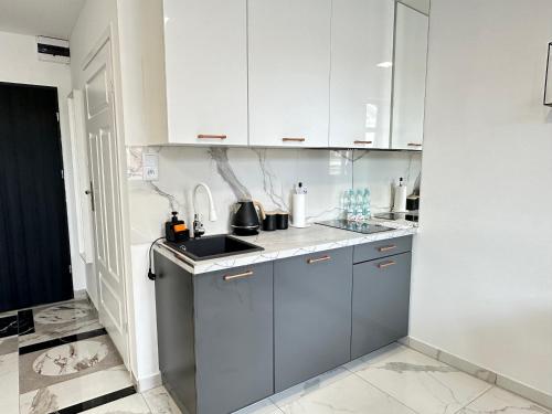 a kitchen with white cabinets and a sink at MOVEEN! Wynajem apartamentów we Wrocławiu! 10 minut od centrum in Wrocław