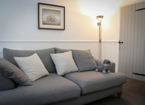 a gray couch with pillows and a teddy bear on it at Newly Refurbished 2-Bed with Patio, Netflix & Wi-Fi in Worksop