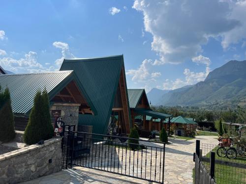 a building with a green roof with mountains in the background at Ethno House Bektesevic in Gusinje