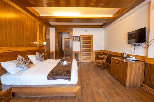a bedroom with a large bed and a television at Vivaan The Sunrise in Manāli