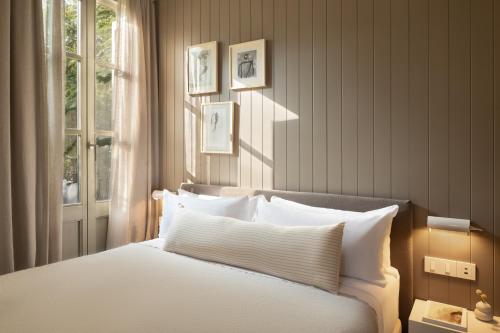 una camera da letto con un letto con cuscini bianchi e una finestra di Hotel Casa Teva Barcelona a Barcellona