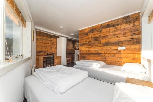 two beds in a room with a wooden wall at Statsbuene i Kabelvåg in Kabelvåg