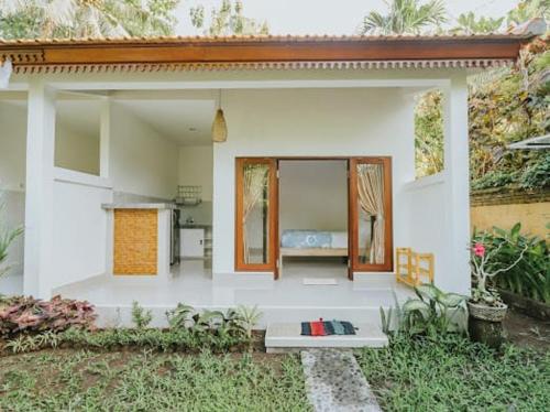 a small white house with a bench in the yard at umahananda in Mambat