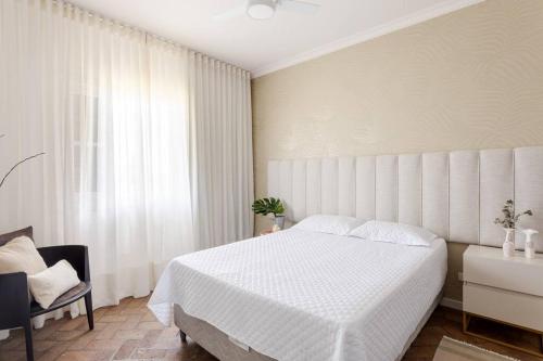 a bedroom with a white bed and a window at Sítio da malva in Sorocaba
