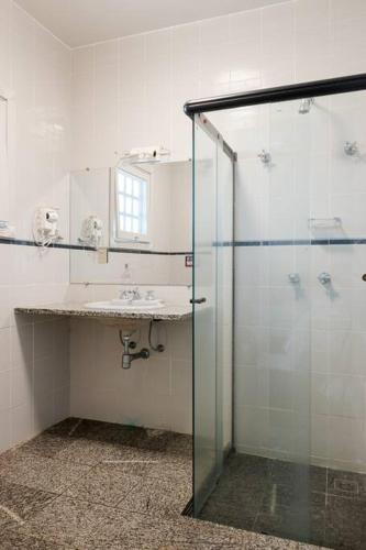a bathroom with a glass shower and a sink at Sítio da malva in Sorocaba