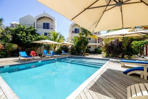 een zwembad met ligstoelen en parasols bij een hotel bij Belize Beachfront Apartment in San Pedro