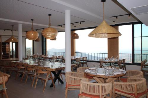 une salle à manger avec tables, chaises et fenêtres dans l'établissement Le Belvedere, à Lavatoggio