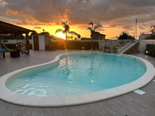 a large swimming pool with a sunset in the background at Villa El Secreto Luxury con piscina, sauna e idromassaggio, vicina al mare e montagna in Borgetto