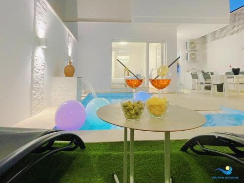 two wine glasses on a table in a room with balloons at VILLA PERLA del SALENTO con piscina in Lido Marini