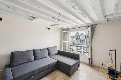 un salon avec un canapé et une grande fenêtre dans l'établissement Orsay Invalides - Lille 1bdr by B'Your Home, à Paris