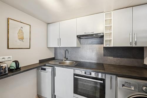 une cuisine avec des armoires blanches et un évier dans l'établissement Orsay Invalides - Lille 1bdr by B'Your Home, à Paris