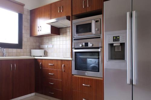 a kitchen with wooden cabinets and stainless steel appliances at Villa Vounos - 5 Bedroom all en-suit with pvt pool in Pissouri