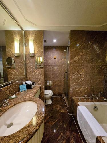 a bathroom with a sink and a tub and a toilet at Jin Jiang Hotel Shanghai - historical hotel in the city-center of Huaihai shopping area and convenient access to metro lines in Shanghai