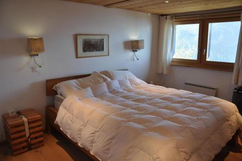 a bedroom with a large white bed with a window at Taveyannaz in Taveyannaz