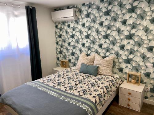 a bedroom with a bed with a floral accent wall at «Au Renard»,proche d’Europa-Park,Strasbourg,Colmar in Herbsheim