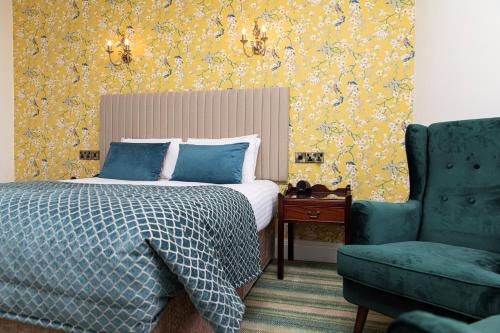 a bedroom with a bed and a blue chair at The Atholl Palace in Pitlochry