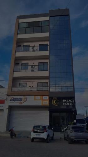 a tall building with cars parked in front of it at LC Palace Hotel in Capim Grosso