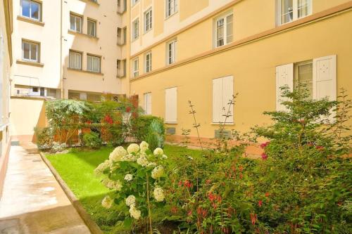 un jardin avec des fleurs devant un immeuble dans l'établissement Charmant studio - Paris Boulogne Marcel Sembat, à Boulogne-Billancourt