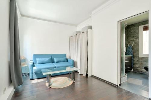 un salon avec un canapé bleu et une table dans l'établissement Charmant studio - Paris Boulogne Marcel Sembat, à Boulogne-Billancourt